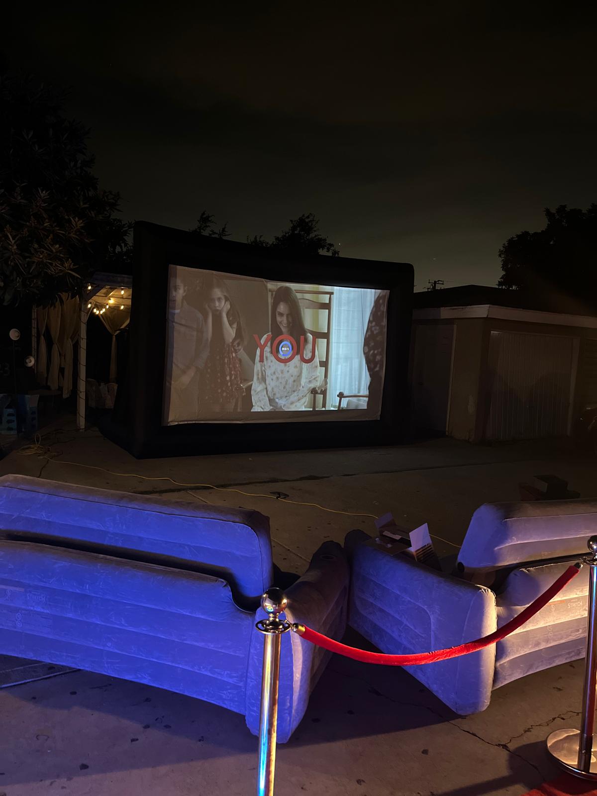 Outdoor movie screen rental with inflatable lounge seating and red carpet in Los Angeles backyard