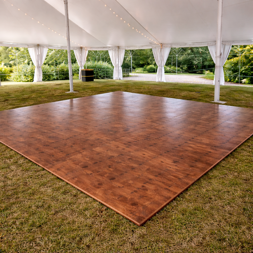 Wood dance floor installed on grass under a white event tent with curtains