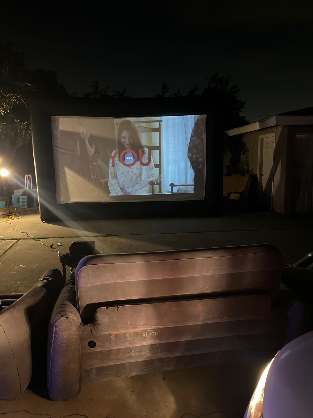 Outdoor movie screen setup on driveway with inflatable seating